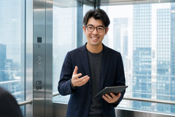 ガラス張りエレベーターでプレゼンする男性
