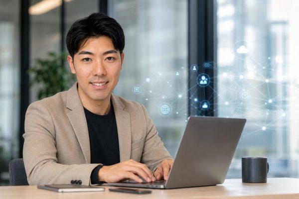 ノートPCとデジタルアイコンに囲まれる男性