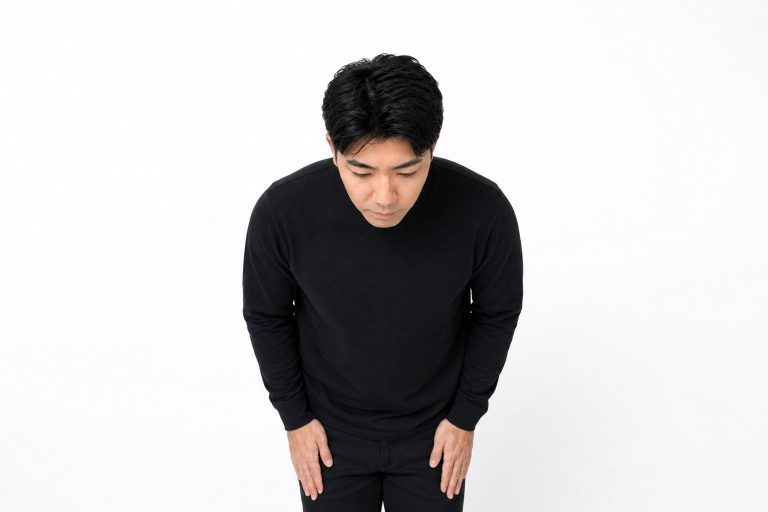 謝罪のお辞儀をする男性(白背景)