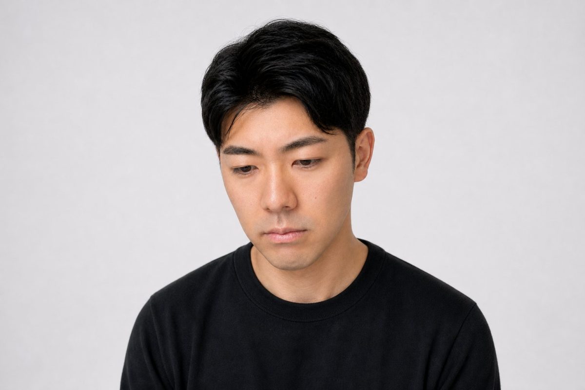 悲しげにうつむく男性(白背景)