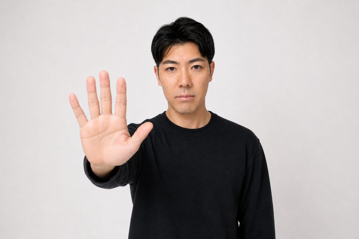 正面に手をかざしてストップする男性(白背景)