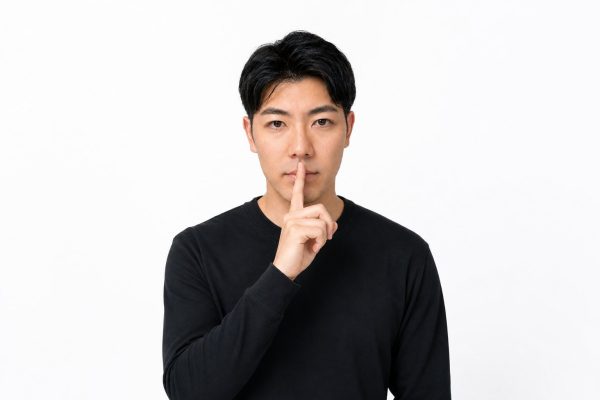 口元に指を当てて静かにと伝える男性(白背景)