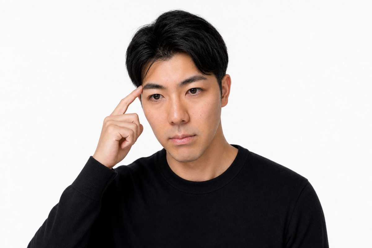こめかみに指を当てて思い出す男性(白背景)