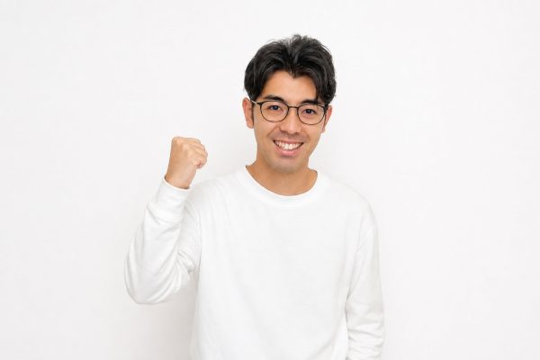 力強くガッツポーズする男性(白背景)