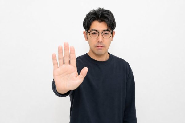 手で制止のポーズをとる男性(白背景)