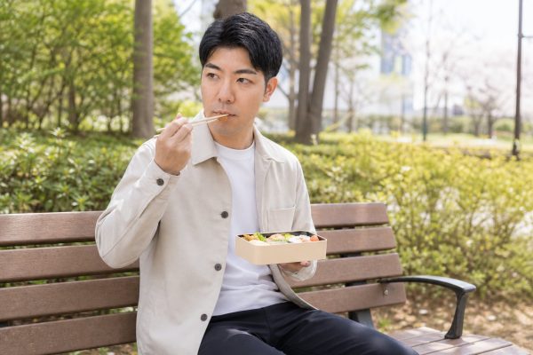 公園のベンチでお弁当を食べる男性
