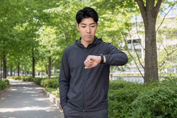 屋外でスマートウォッチを確認する男性