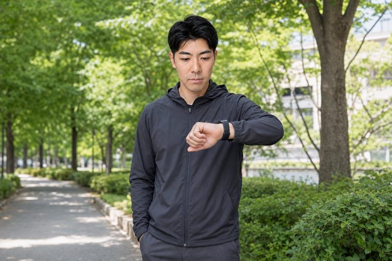 屋外でスマートウォッチを確認する男性