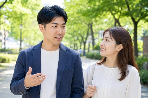 並木道を歩きながら会話するカップル