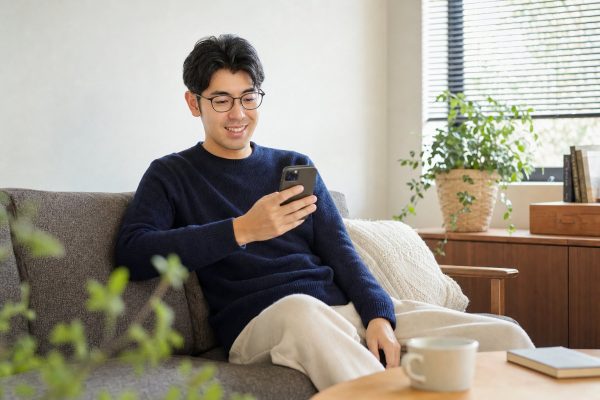 ソファでスマホをチェックする男性