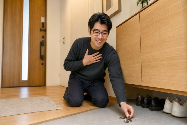 玄関で鍵を見つけて安心する男性